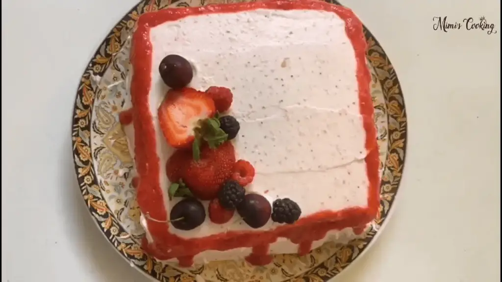 A strawberry cake topped with two fresh strawberries cut in half